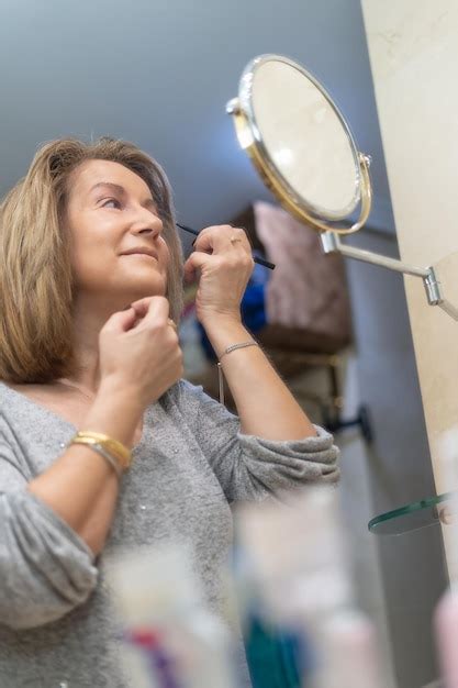 Premium Photo Mature White Woman Applying Beauty Treatments In Front Of The Mirror Of Her Bathroom