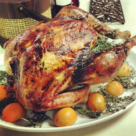 a roasted turkey on a plate with oranges and herbs