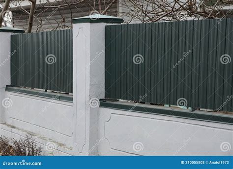 Part Of Fence Of Green Metal And White Concrete Pillars Stock Image