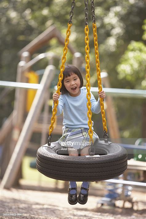 Girl On Tire Swing In Playground Smiling Portrait High Res Stock Photo