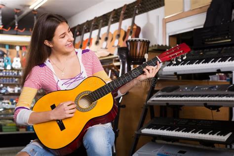 Feliz Clienta Femenina Tratando De Tocar Nueva Guitarra Imagen De