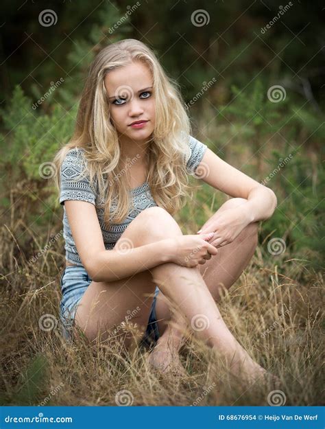 Ładny Blond Nastolatka Obsiadanie W Trawie Zdjęcie Stock Obraz złożonej z guzik trawy