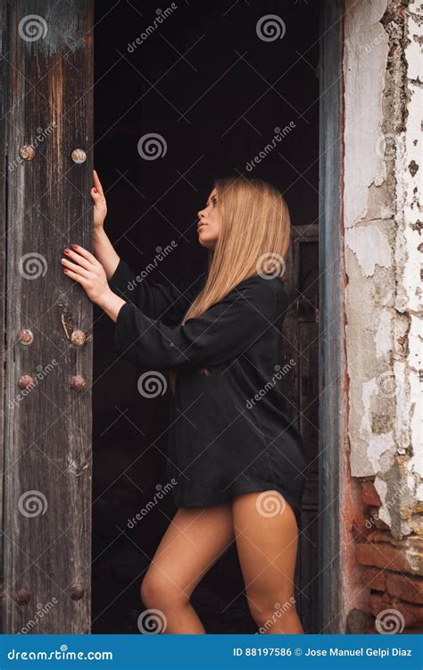 Sensual Blonde Girl In Black Shirt Waiting Near A Door Stock Photo