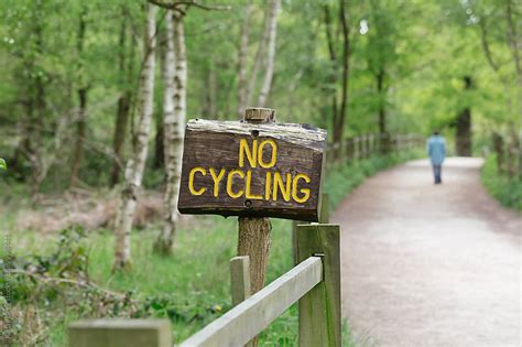 No Cycling Sign On Trail With Anonymous Person Walking In Distance By
