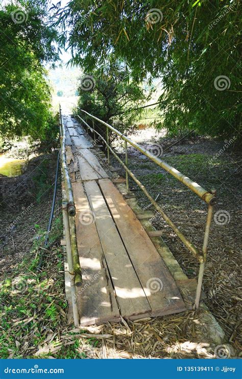 Rustic Foot Bridge With Bamboo Railing And Wooden Planks In Rural Laos