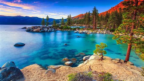 Calm Body Of Water Surrounded By Mountains And Rocks With Trees Under