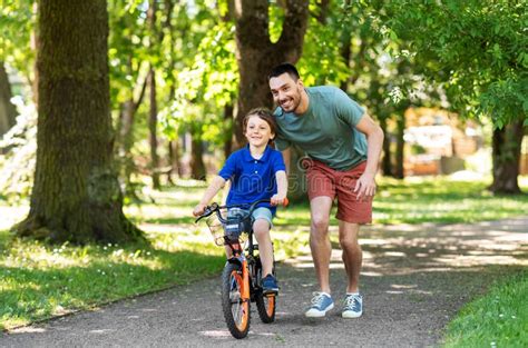 Padre Enseñando A Su Pequeño Hijo A Montar En Bicicleta En El Parque