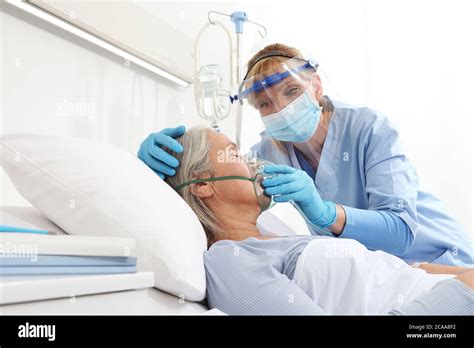 Nurse Puts Oxygen Mask On Elderly Woman Patient Lying In The Hospital Room Bed Wearing