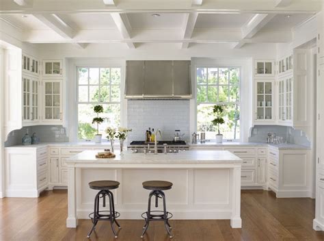 White and navy kitchen features iron and glass cage lanterns over navy center island accented with x trim moldings love the chair, fireplace, dark wood floors and ceiling beams. Example of a small classic u-shaped dark wood floor open concept kitchen design in Seattle with ...