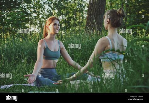 Two Young Women Doing Yoga Padmasana Lotus Pose Outdoor Meditation And