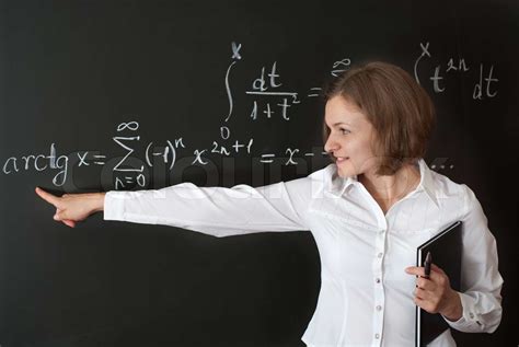 Young Teacher Is Standing Near Blackboard In Classroom Stock Image