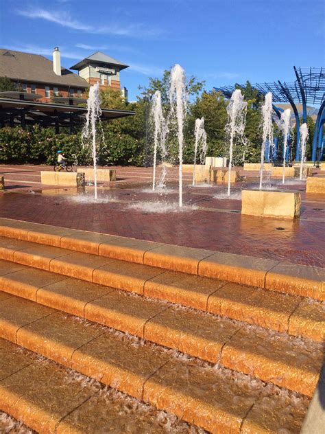 Several Fountains Are Spouting Water In The Center Of A Plaza With