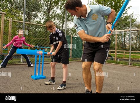 A Male Primary School Teacher Teaching Cricket Skills To Children As