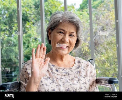 Portrait Of Happy Asian Senior Woman Grey Hair Sitting On Wheelchair Waving Greeting Smiling