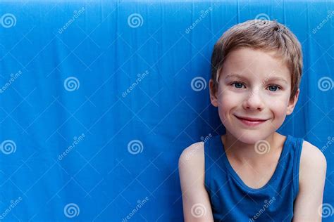 Portrait Of A Cute Smiling Young Boy With Blue Eyes And Wearing A Blue