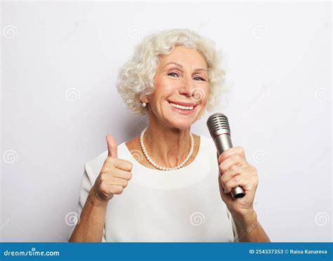Lifestyle And Old People Concept Happy Old Curly Woman Singing With Microphone Over White