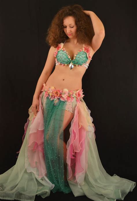 A Woman In A Green And Pink Belly Dance Costume With Flowers On Her Skirt Posing For The Camera