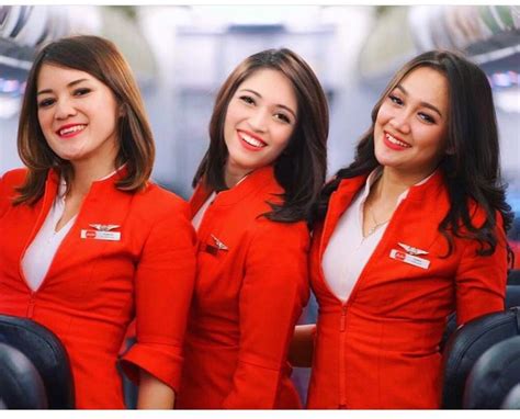 Three Women In Red Uniforms Are Smiling At The Camera While Sitting On An Airplane With Their