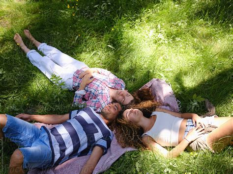 relaxed friends enjoying summer sunlight on meadow stock image everypixel