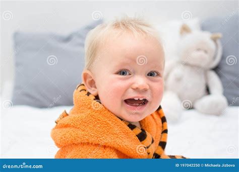 Ten Month Baby Boy Sitting On Bed In Bathrobe And Smiling Kid Face