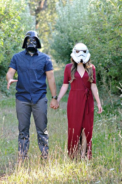 A Man And Woman Wearing Darth Vader Masks Holding Hands