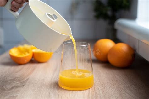 Fresh Orange Juice Pouring From A Juicer Into A Glass With Squeezed