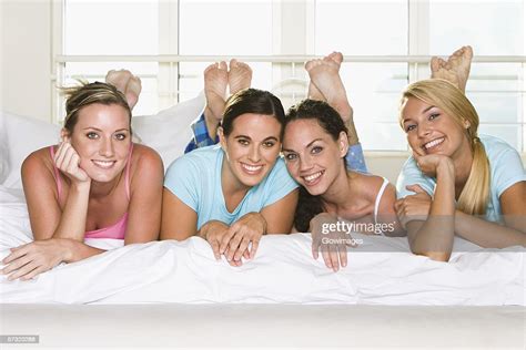 Portrait Of Four Young Women Lying Down Side By Side On A Bed Photo