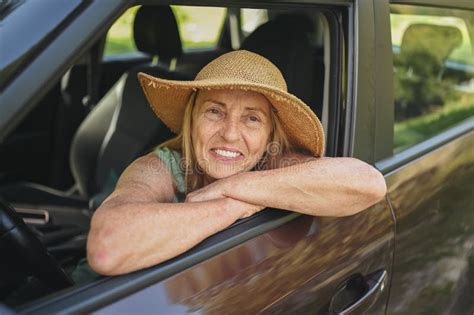 Happy Senior Woman Driver In Straw Hat Driving Sitting In New Car