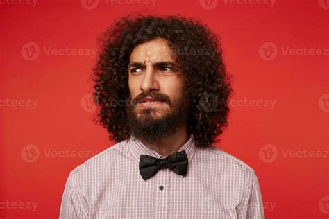 Studio Shot Of Severe Brunette Curly Man With Beard Looking Aside And
