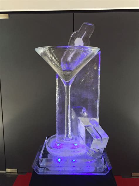 an ice sculpture with a martini glass in the center and a bottle on top that is lit up