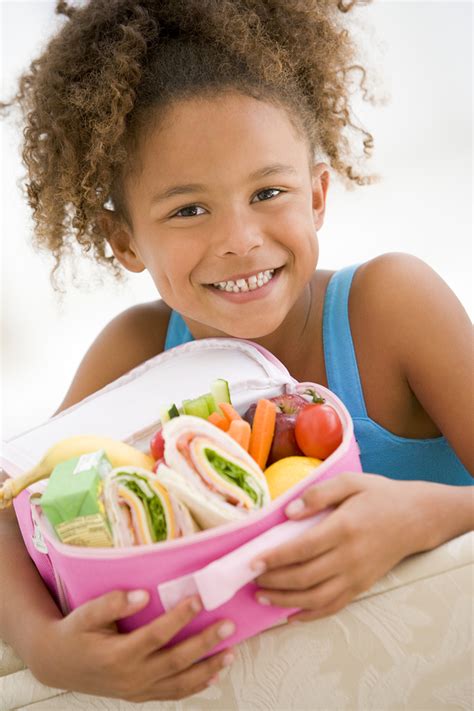 Young Girl Holding Packed Lunch In Living Room Smiling The Therapy Spot