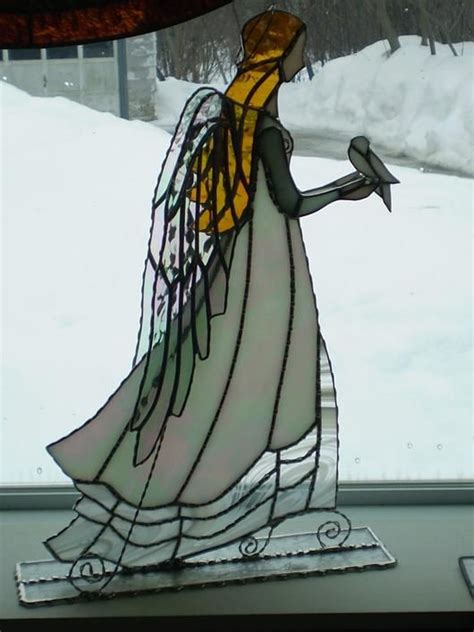 A Stained Glass Angel Holding A Bird In The Snow