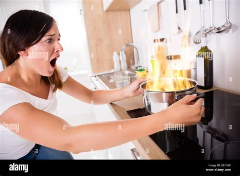 Shocked Young Woman Looking At Burnt Food In Cooking Pot Stock Photo