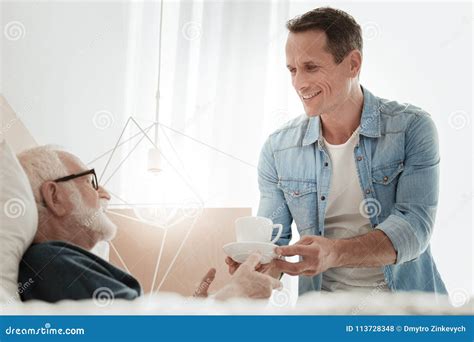 Pleasant Careful Man Smiling And Giving A Cup Stock Photo Image Of