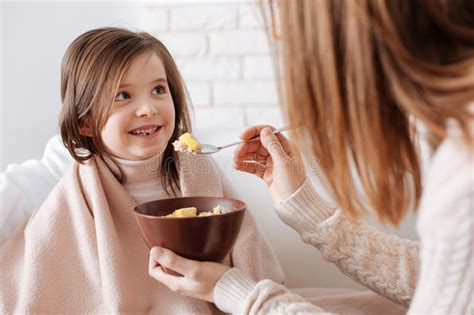Positive Little Girl And Her Mother Senjoying Breakfast Stock Photo