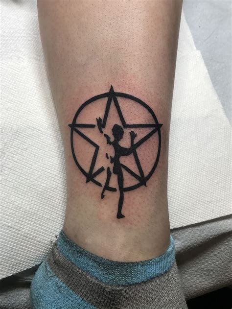 A Person With A Star Tattoo On Their Leg Holding An Arrow And Pointing
