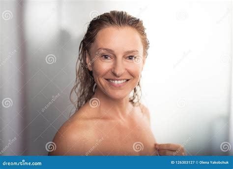 mooie midden oude vrouw die zich bij badkamers na het nemen van douche bevinden stock afbeelding