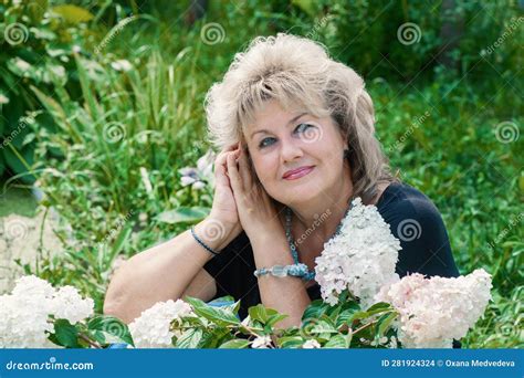 60 Year Old Woman In The Garden A Mature Woman Enjoys The Flowers Of A