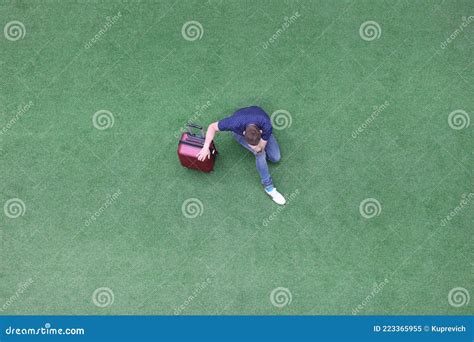 Sad Man With Suitcase Sitting On Green Grass And Holding His Head Top