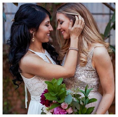 two beautiful women standing next to each other in front of flowers and greenery