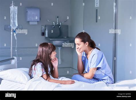 Nurse Talking With Girl Patient Sitting Up In Bed On Hospital Children