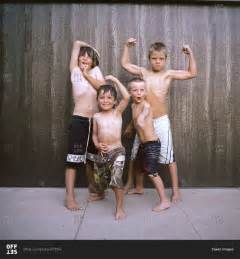 Portrait Of Boys Flexing Muscles While Standing Against Wall Stock