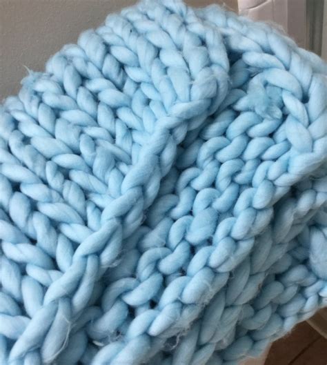 A Blue Knitted Blanket Sitting On Top Of A Wooden Floor Next To A Door
