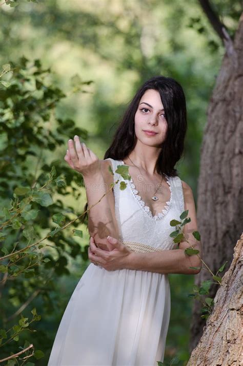 Woman With Long Hair Wearing White Dress Pose In The Forest Stock