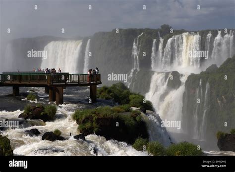 Tourists On Platform Looking Down Over Iguazu Falls On The Brazilian