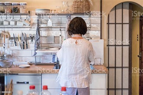 Japanese Woman In Modern Home Kitchen Cooking And Washing Dishes Stock