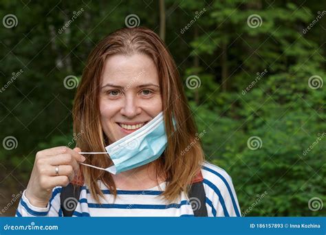 a smiling woman taking off a surgical face mask stock image image of medical girl 186157893