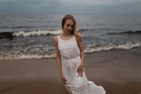 Walking Beautiful Young Blonde Woman Beach Nymph In White Dress Near Sea With Waves During A