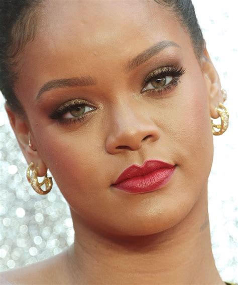 a close up of a person wearing gold earrings and red lipstick with glitter in the background