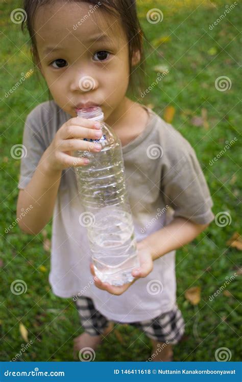 Little Children Drinking Water From Bottle In Green Park Stock Photo